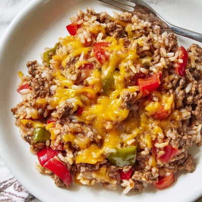 A close-up of the Unstuffed Pepper Skillet reveals tender rice, tomatoes, and savory beef, perfect for a busy weeknight dinner served in a cast-iron pan.