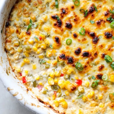 Baked creamy corn jalapeño dip topped with melted cheddar and fresh cilantro garnish