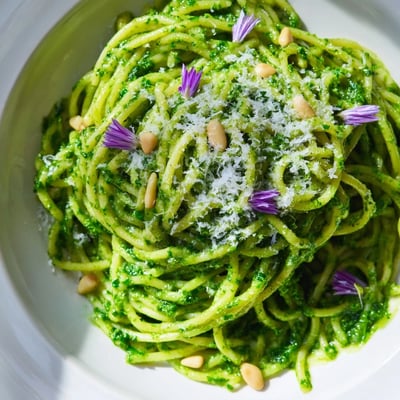 Wild garlic pesto pasta topped with pine nuts and vibrant green herb garnish